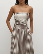 Woman wearing a strapless striped dress in beige and brown