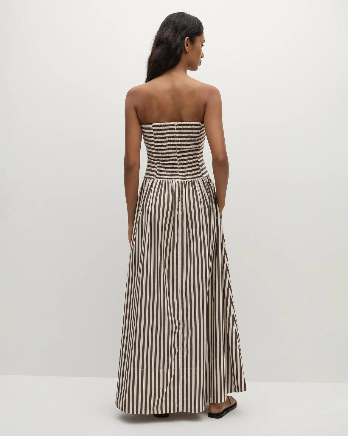 Woman wearing a strapless striped dress in beige and brown
