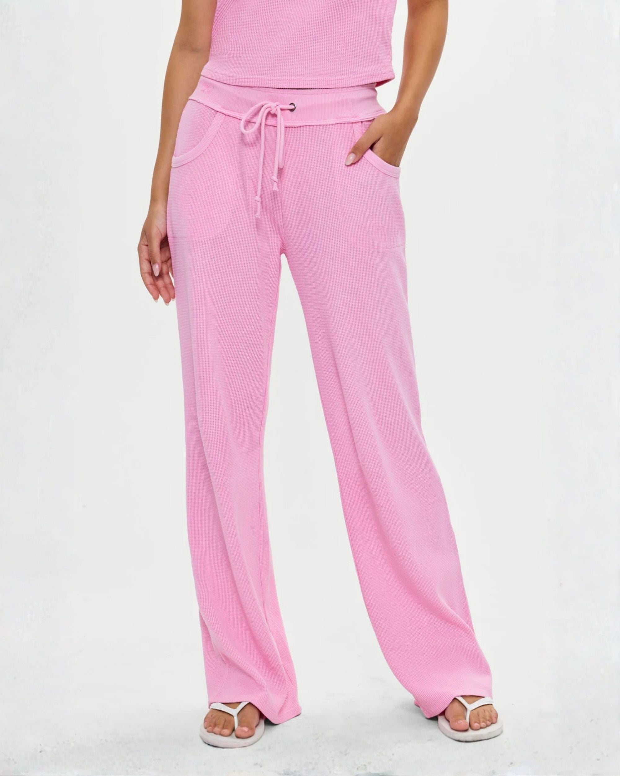 a woman is wearing waffle knit joggers in neon pink by Frankies Bikinis