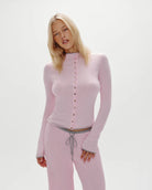 Woman wearing a pink ribbed long-sleeve button down top and pants 