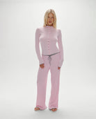 Woman wearing a pink ribbed long-sleeve button down top with grey trim and matching pants