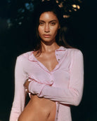 Woman wearing a pink ribbed long-sleeve button down top with grey trim