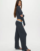 Woman wearing a dark gray button-up ribbed top in dark grey with a pale blue trim with matching pants