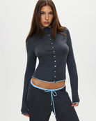 Woman wearing a dark gray button-up ribbed top in dark grey with a pale blue trim