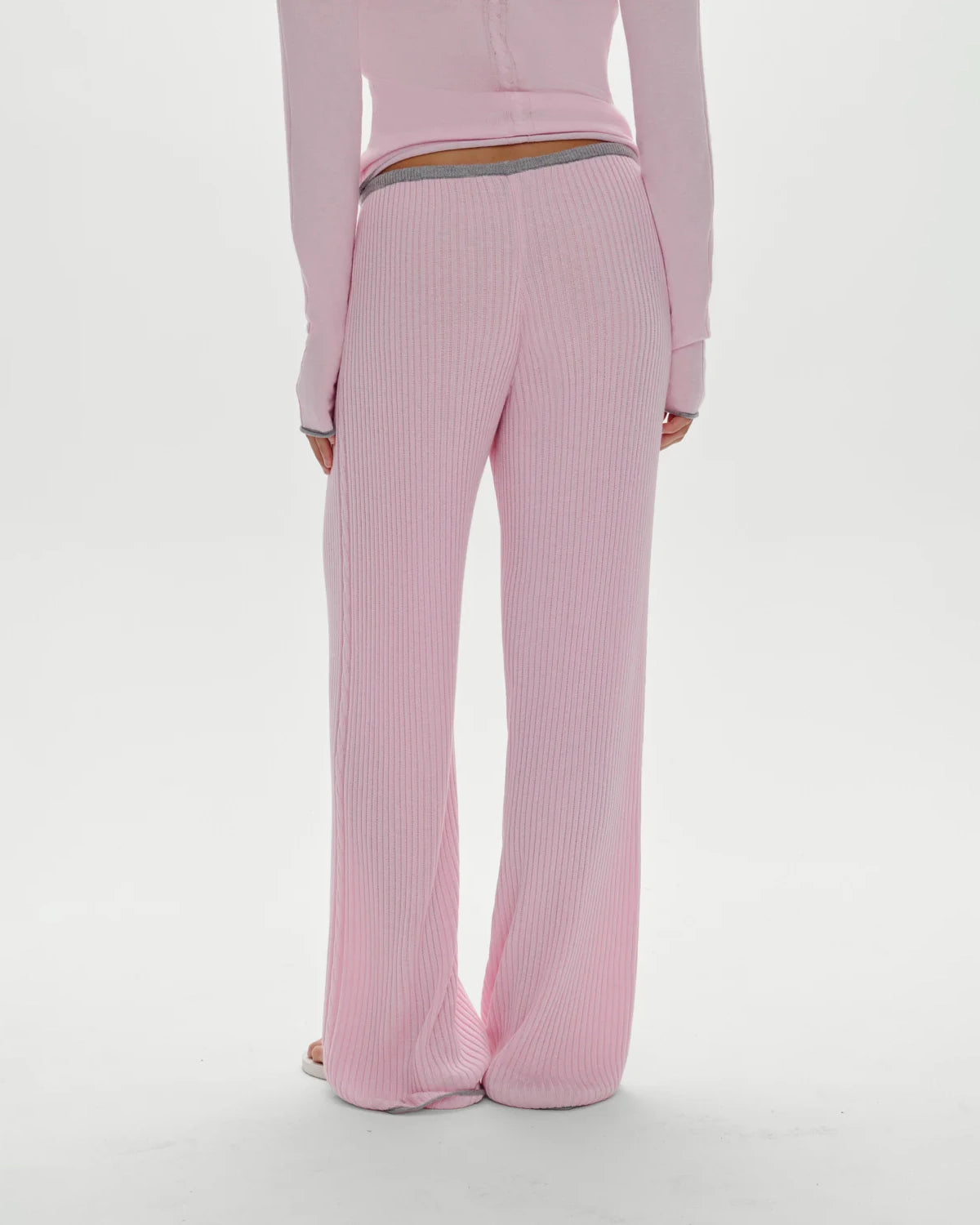 A woman wearing a pink ribbed lounge pant with grey drawstring and trim
