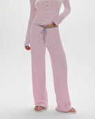 A woman wearing a pink ribbed lounge pant with grey drawstring and trim