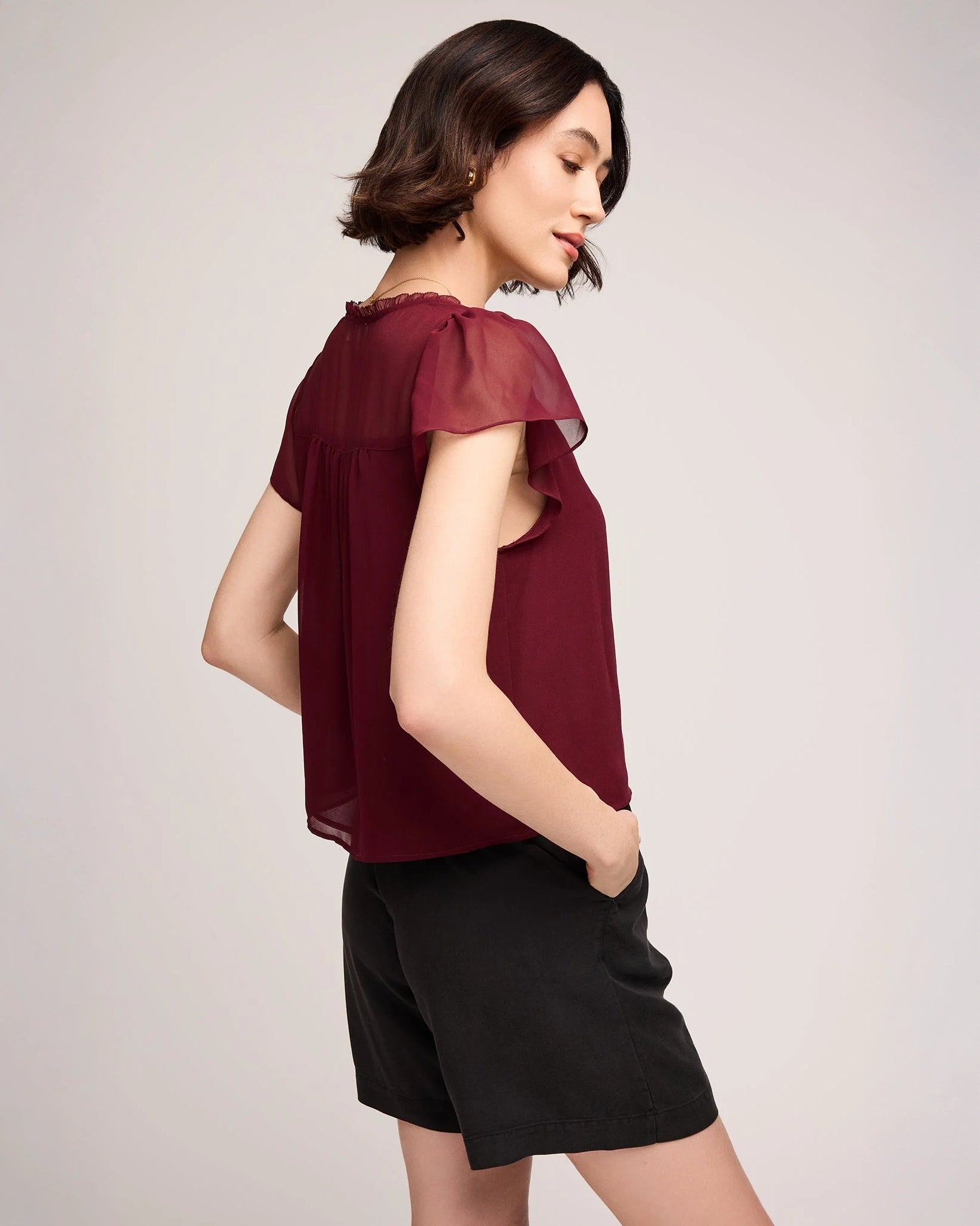 Woman wearing a burgundy button down blouse with butterfly sleeve