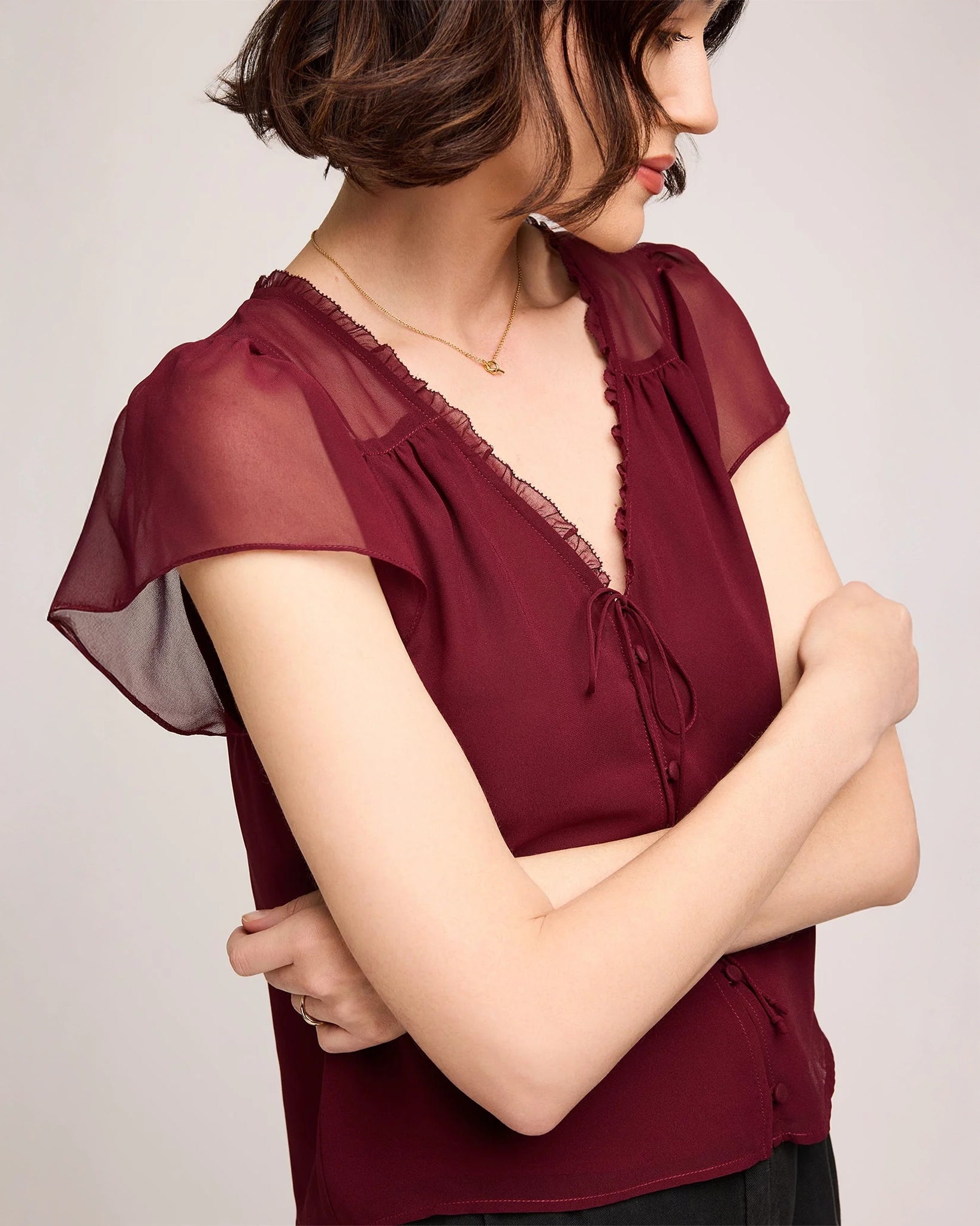 Woman wearing a burgundy button down blouse with butterfly sleeve