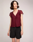 Woman wearing a burgundy button down blouse with butterfly sleeve