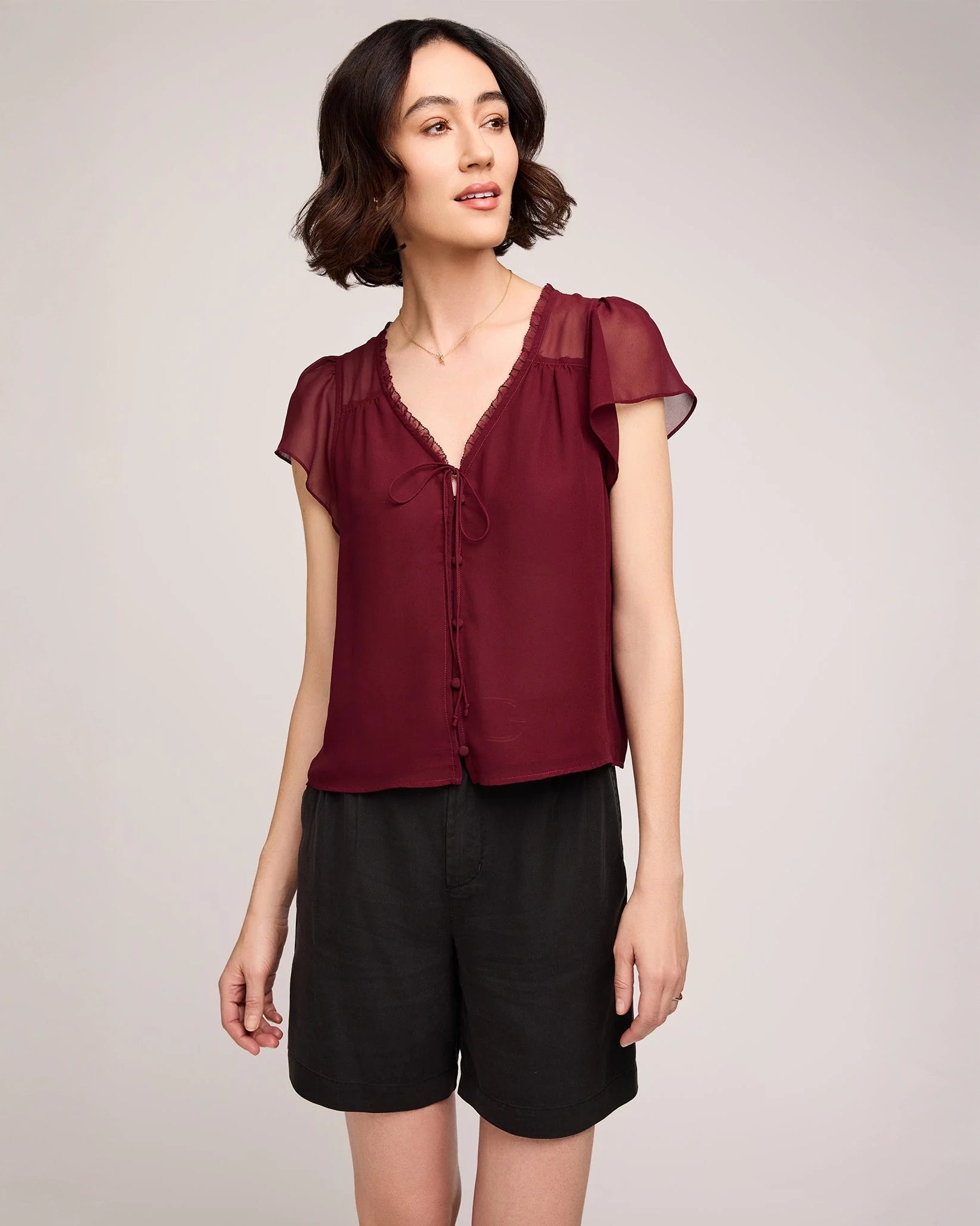 Woman wearing a burgundy button down blouse with butterfly sleeve
