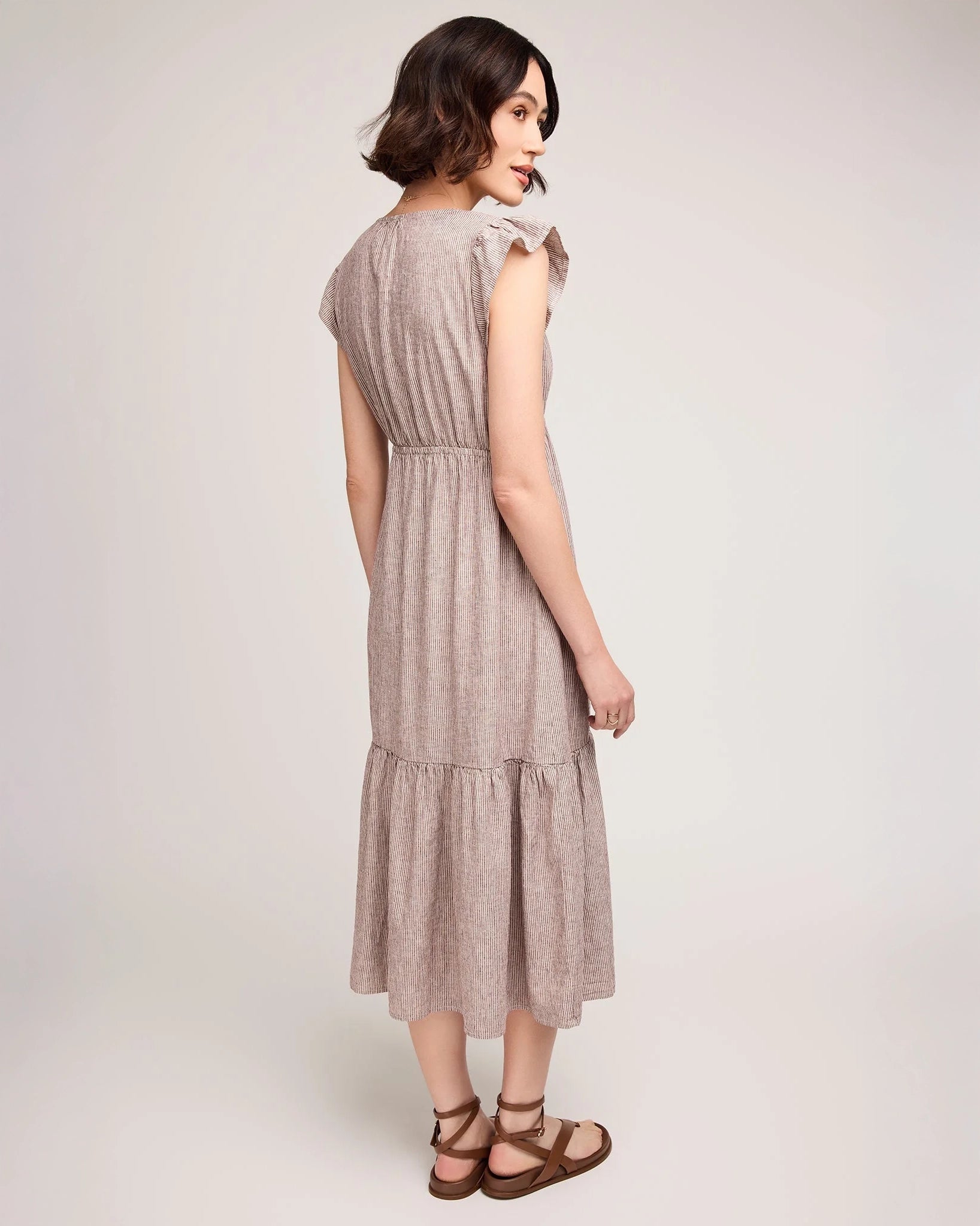woman wearing linen dress with tiered skirt and  burgundy stripe 