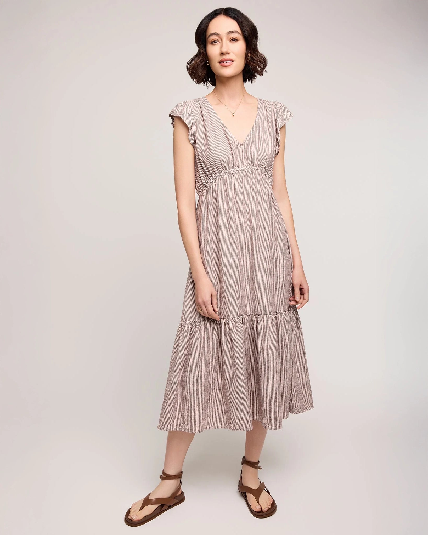 woman wearing linen dress with tiered skirt and  burgundy stripe 