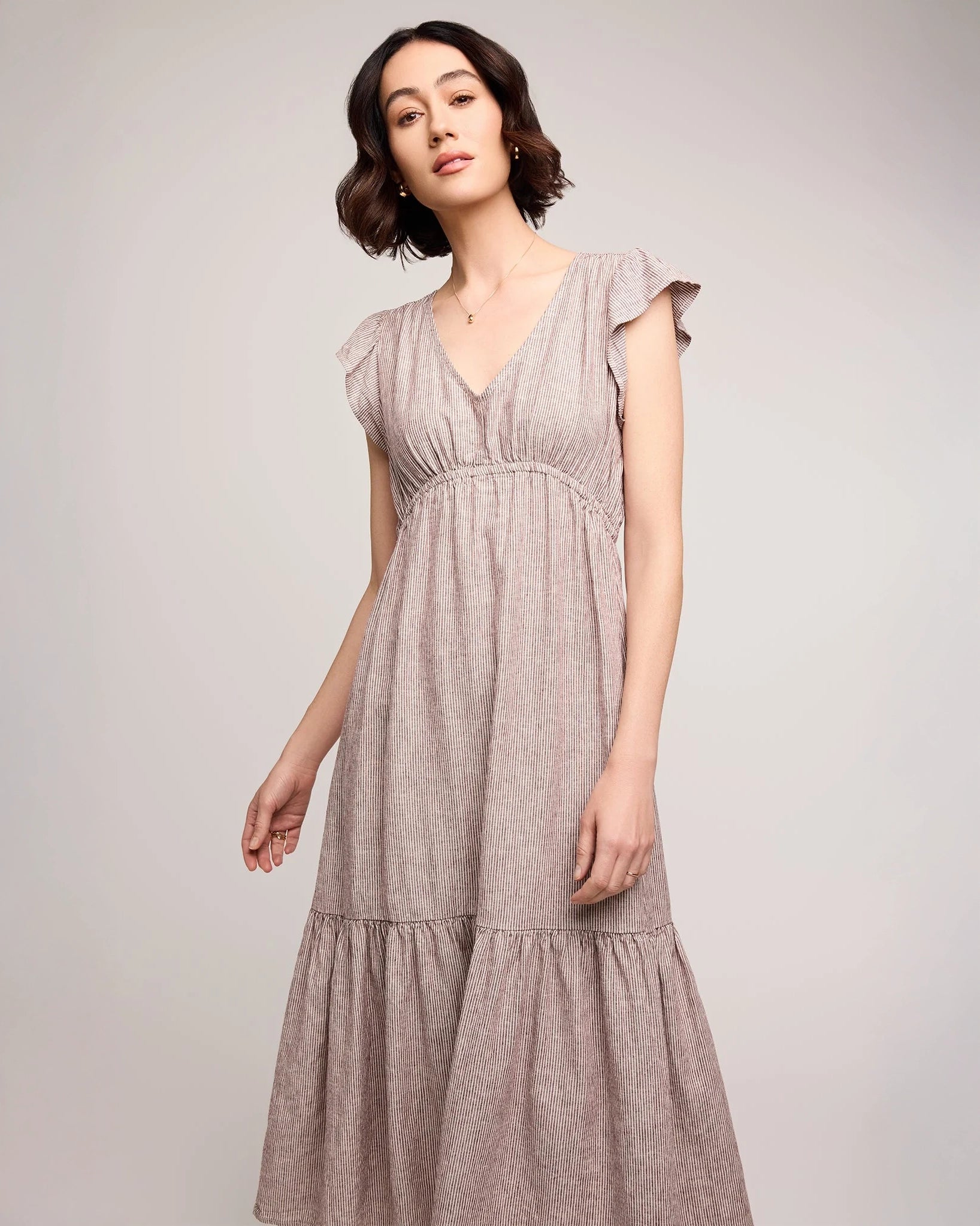 woman wearing linen dress with tiered skirt and  burgundy stripe 
