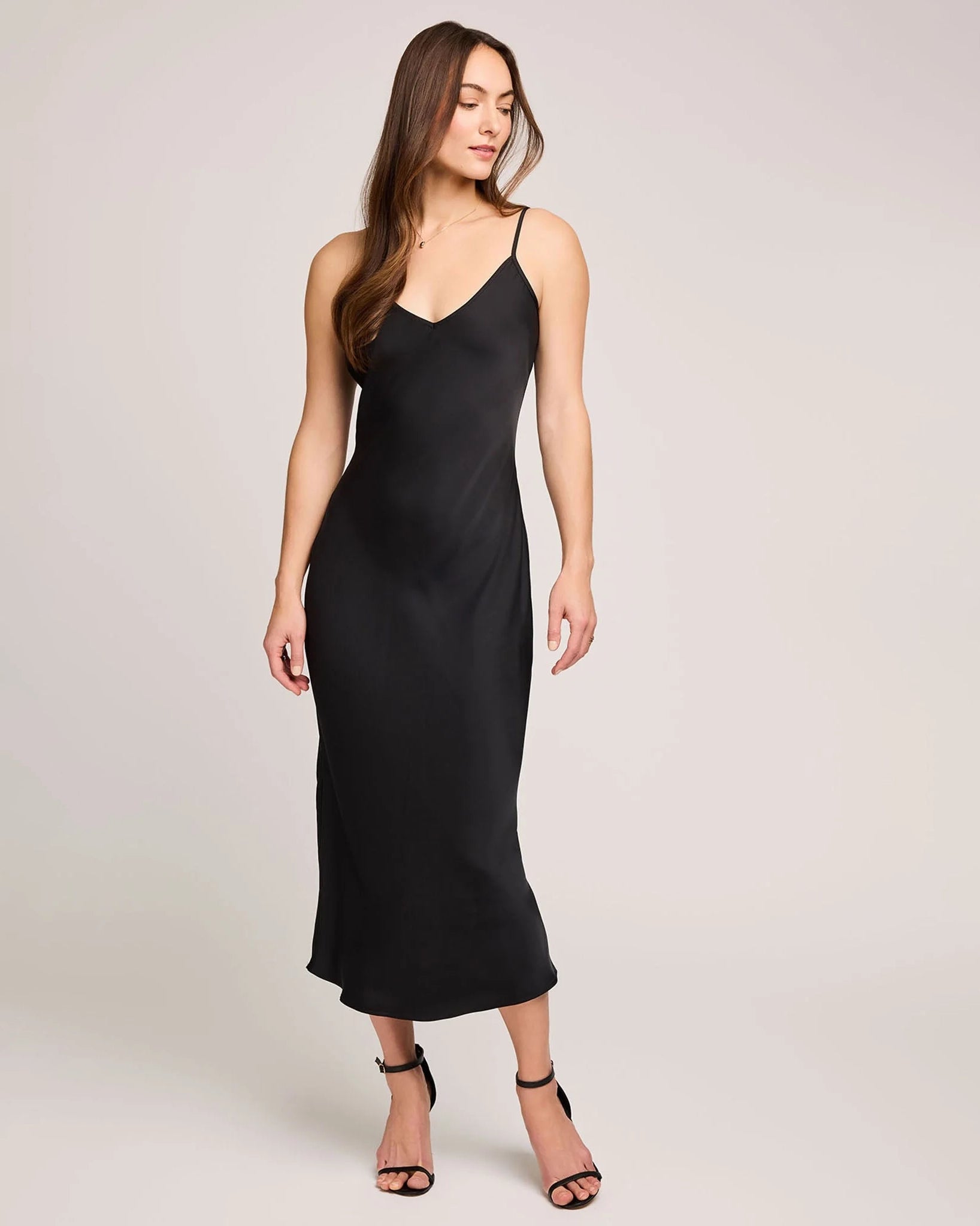 woman wearing a black satin slip dress with midi length