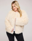 a plus sized woman wearing a faux fur jacket in cream