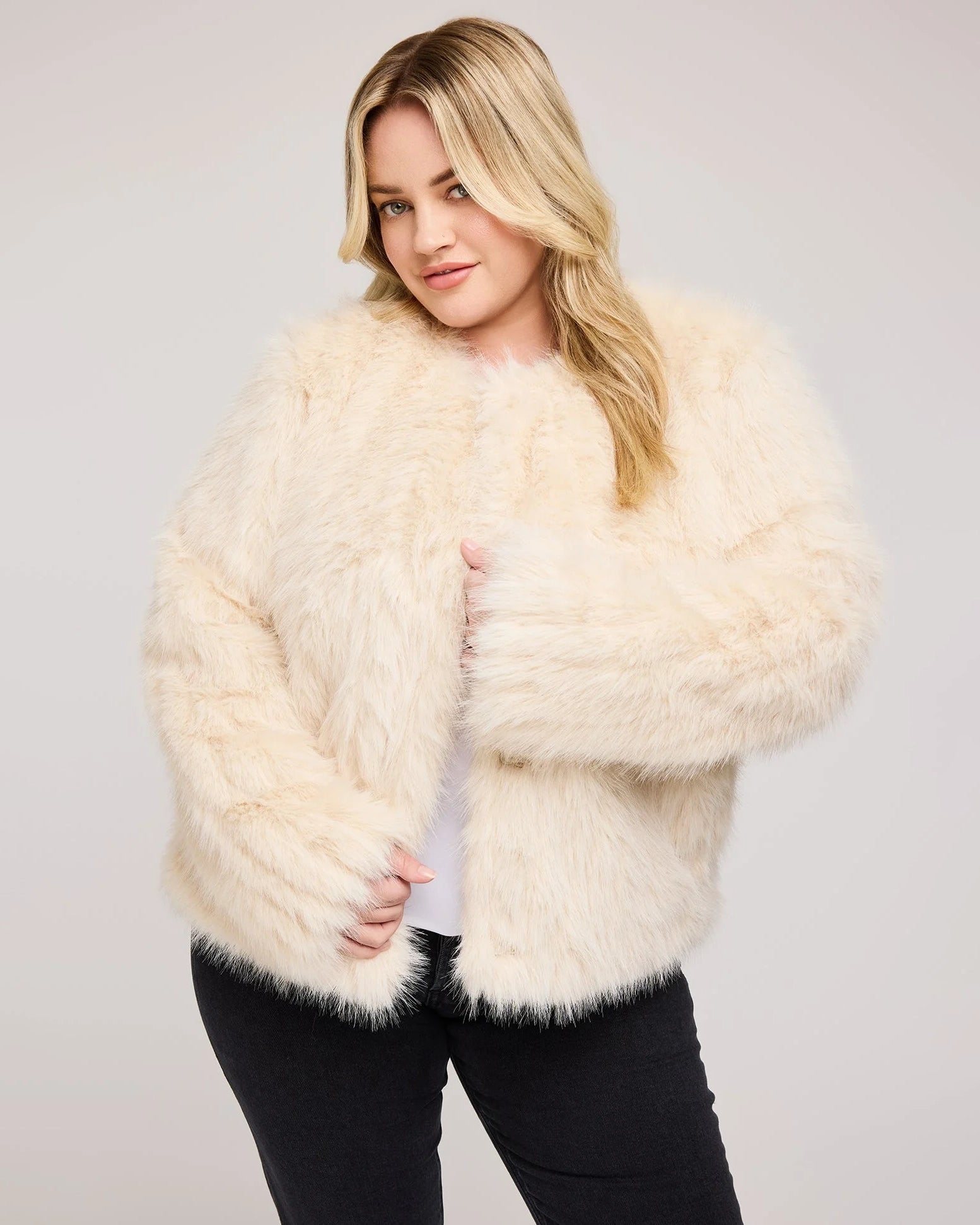 a plus sized woman wearing a faux fur jacket in cream