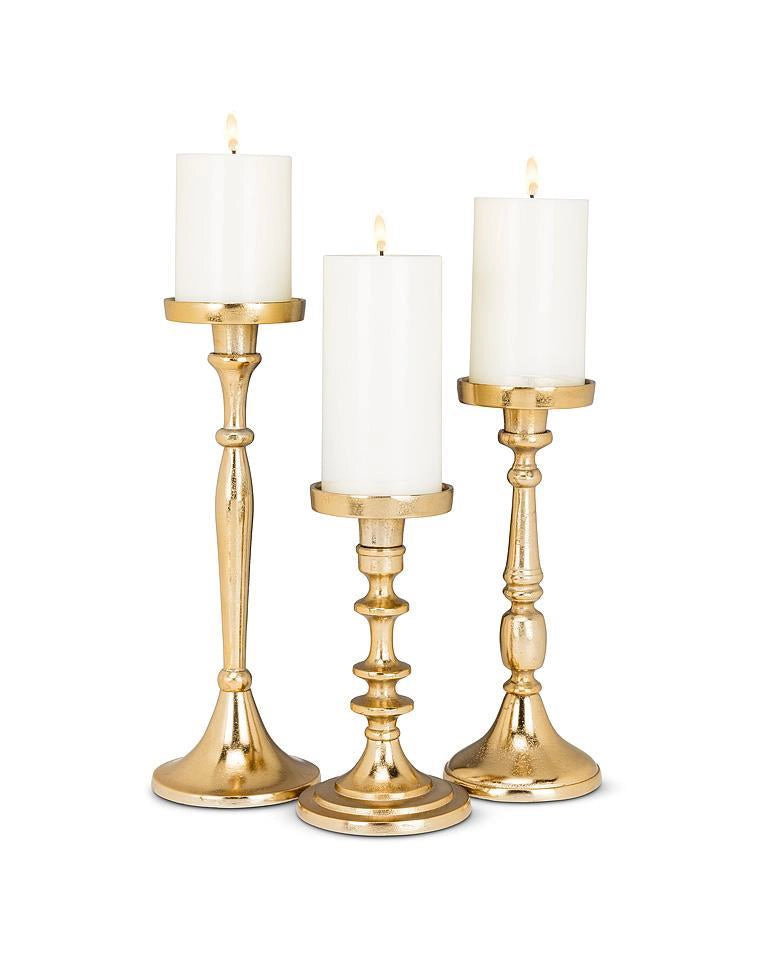 three gold candle holders with pillar candles in 3 different sizes: small, medium and large