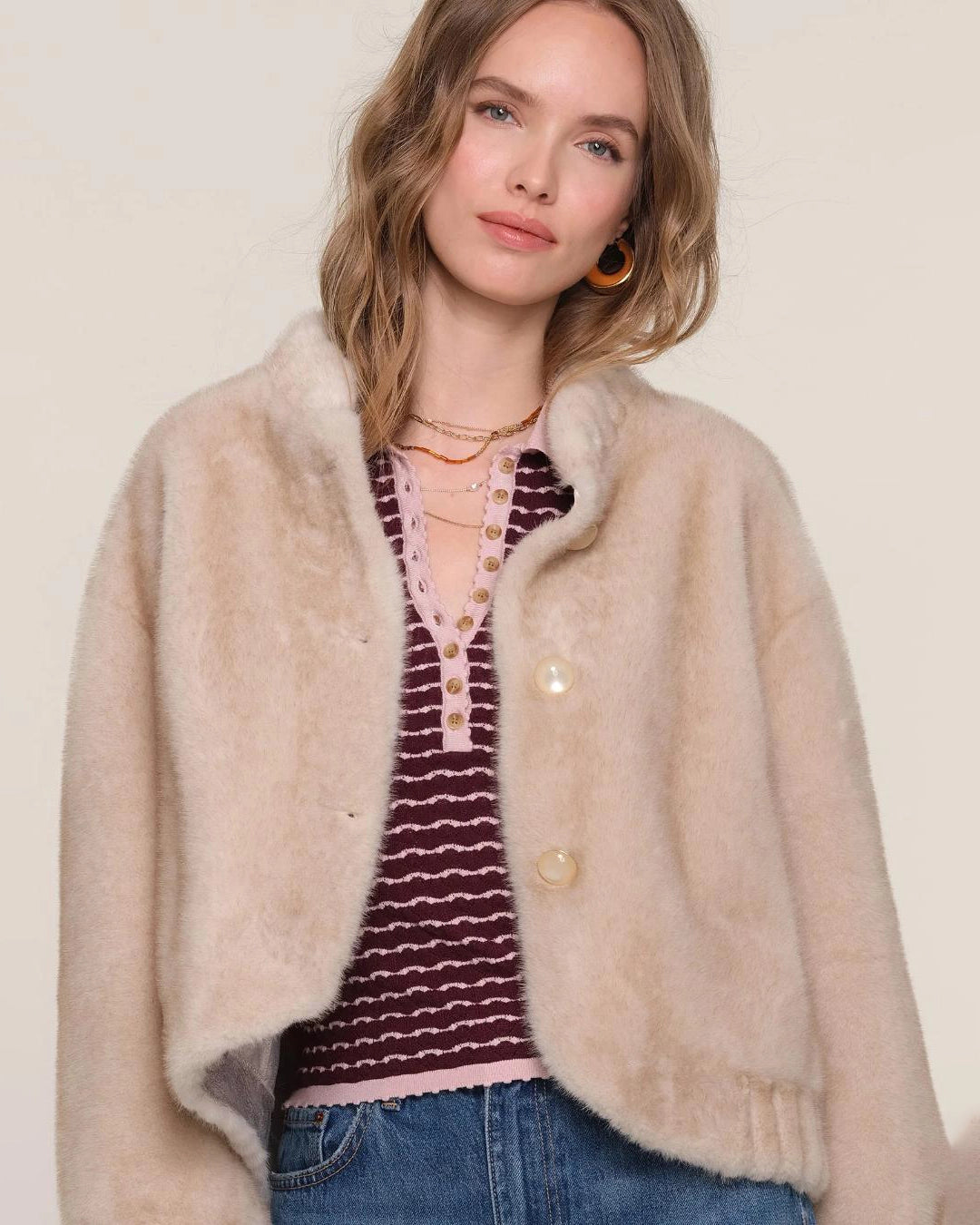 a woman wears a faux fur jacket in a light colour