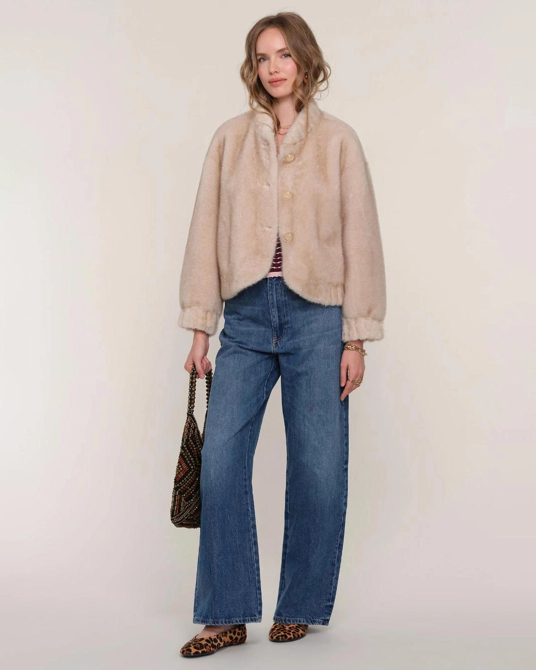 a woman wears a faux fur jacket in a light colour