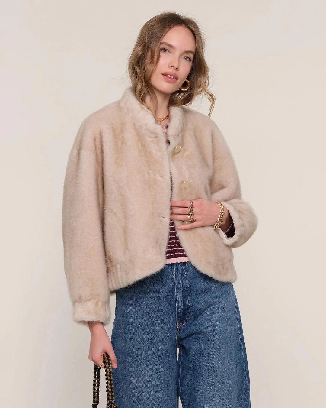 a woman wears a faux fur jacket in a light colour