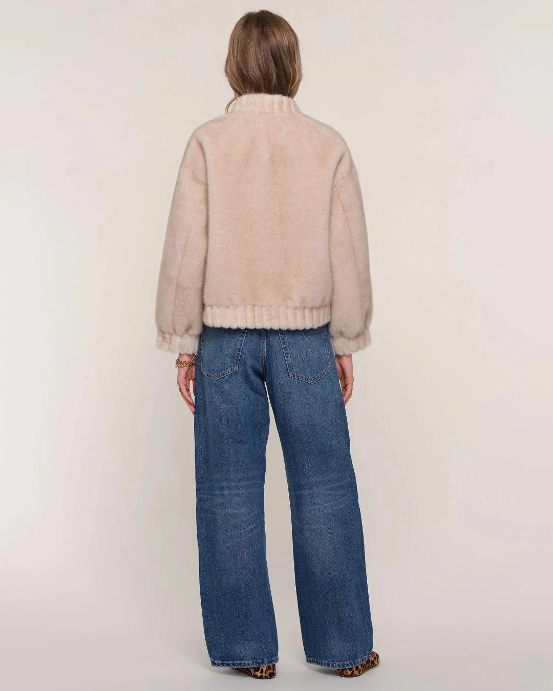 a woman wears a faux fur jacket in a light colour
