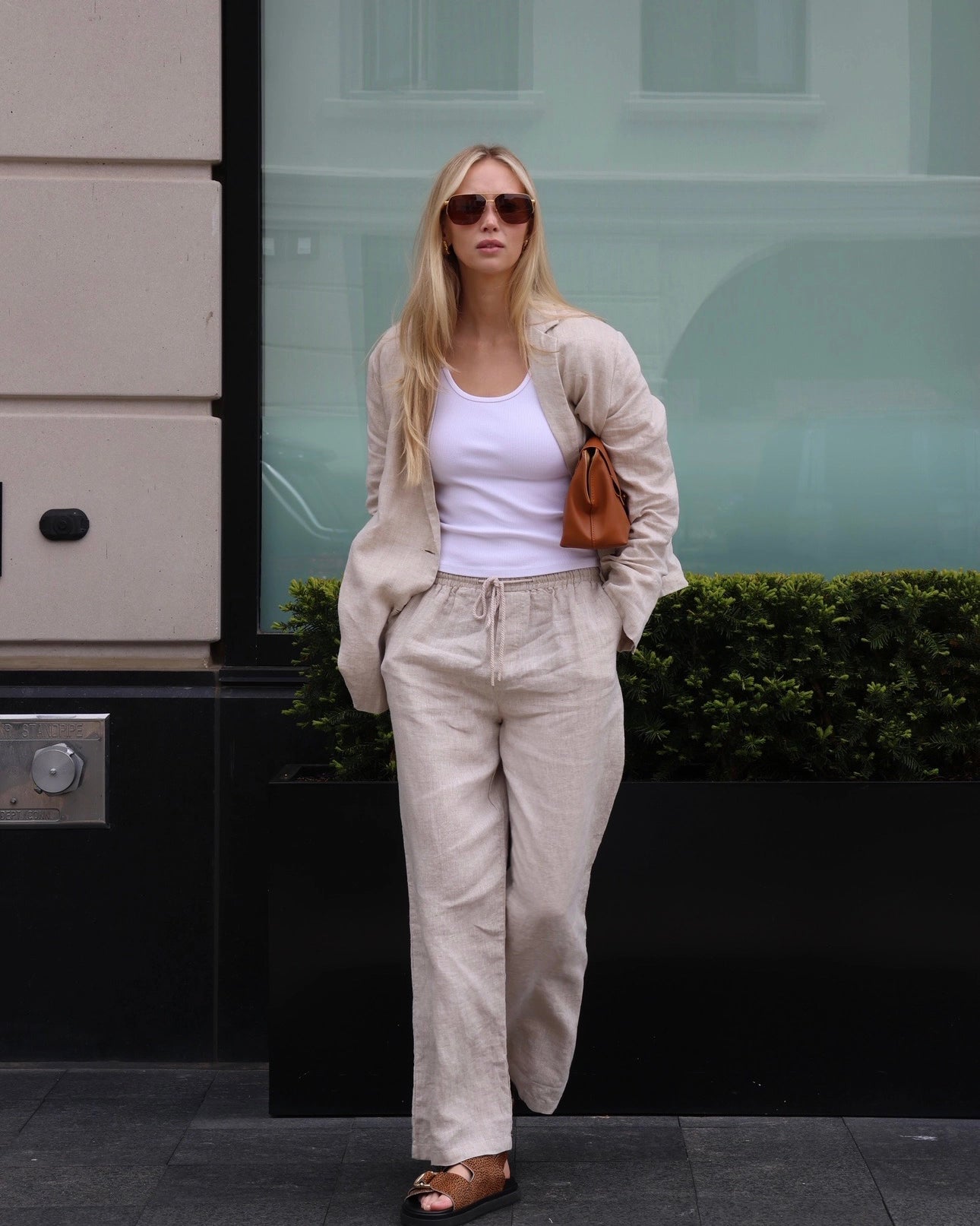 Woman wearing a beige linen blazer, white top, and linen pants