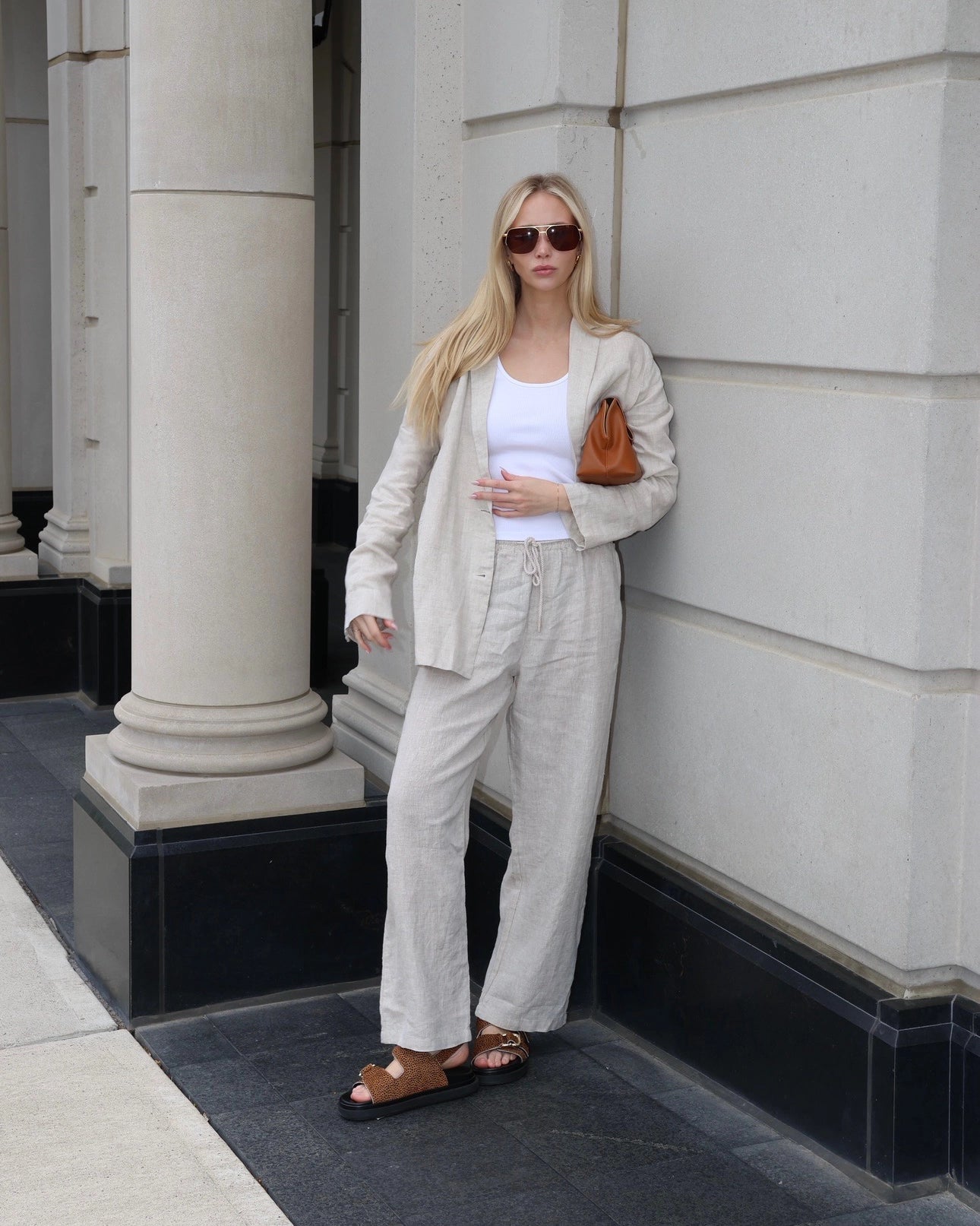 Woman wearing a beige linen blazer, white top, and linen pants