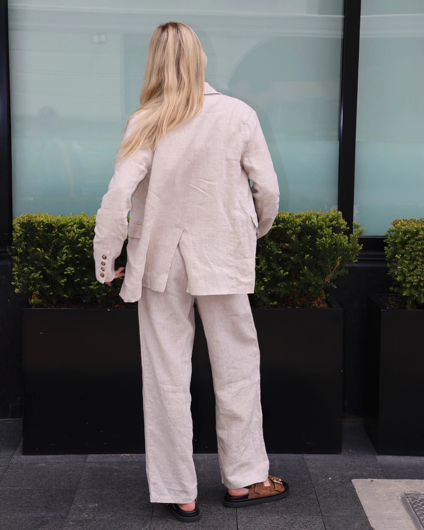 Woman wearing a beige linen blazer, white top, and linen pants