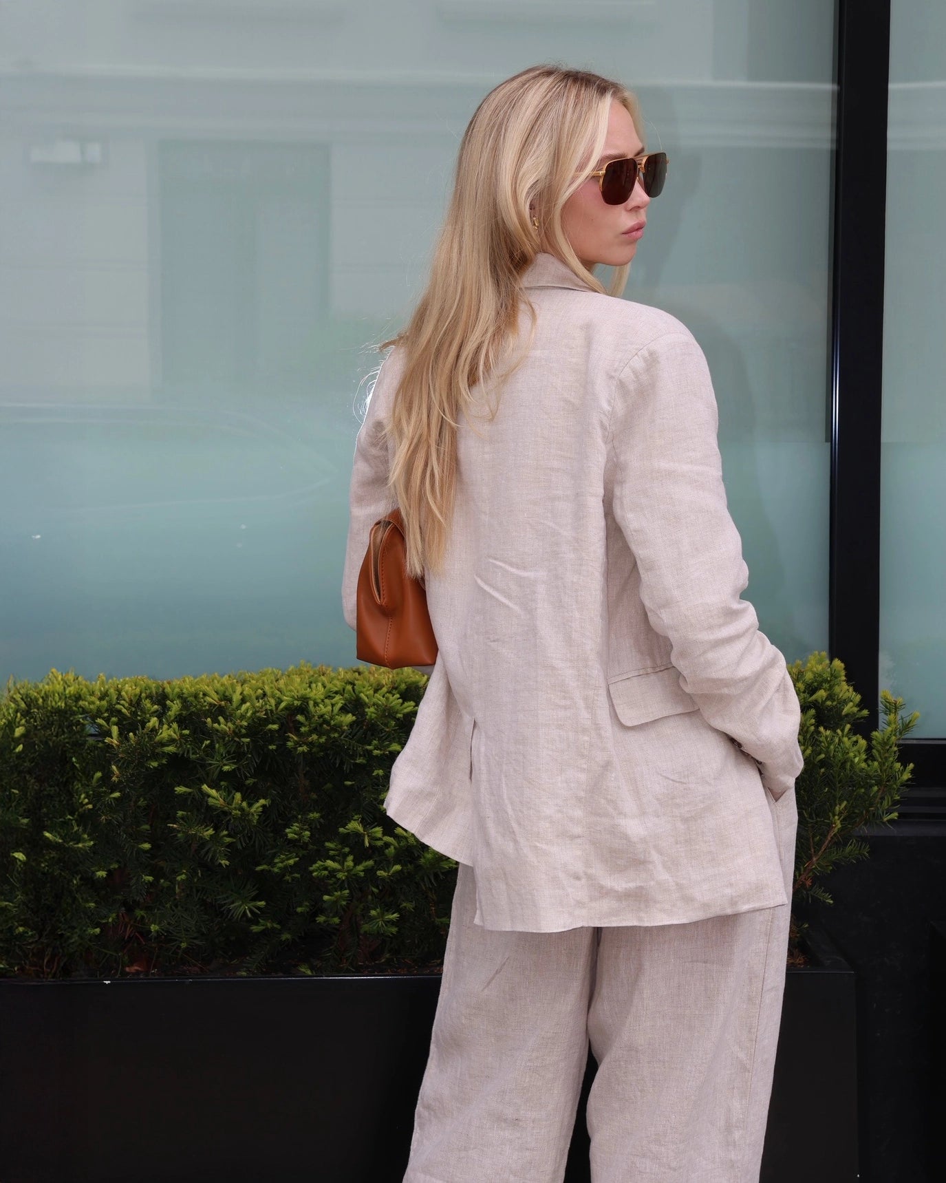Woman wearing a beige linen blazer, white top, and linen pants