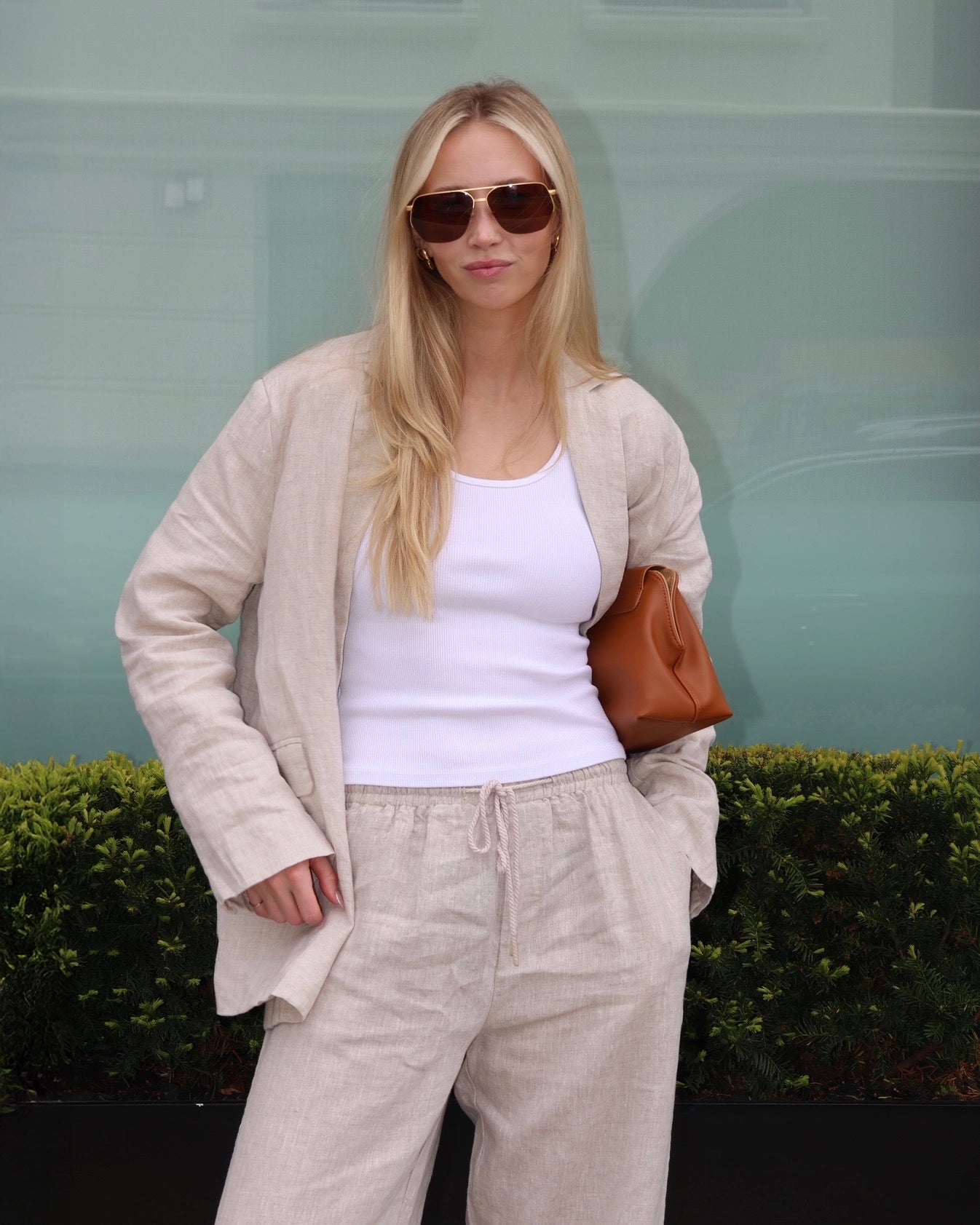 Woman wearing a beige linen blazer, white top, and linen pants