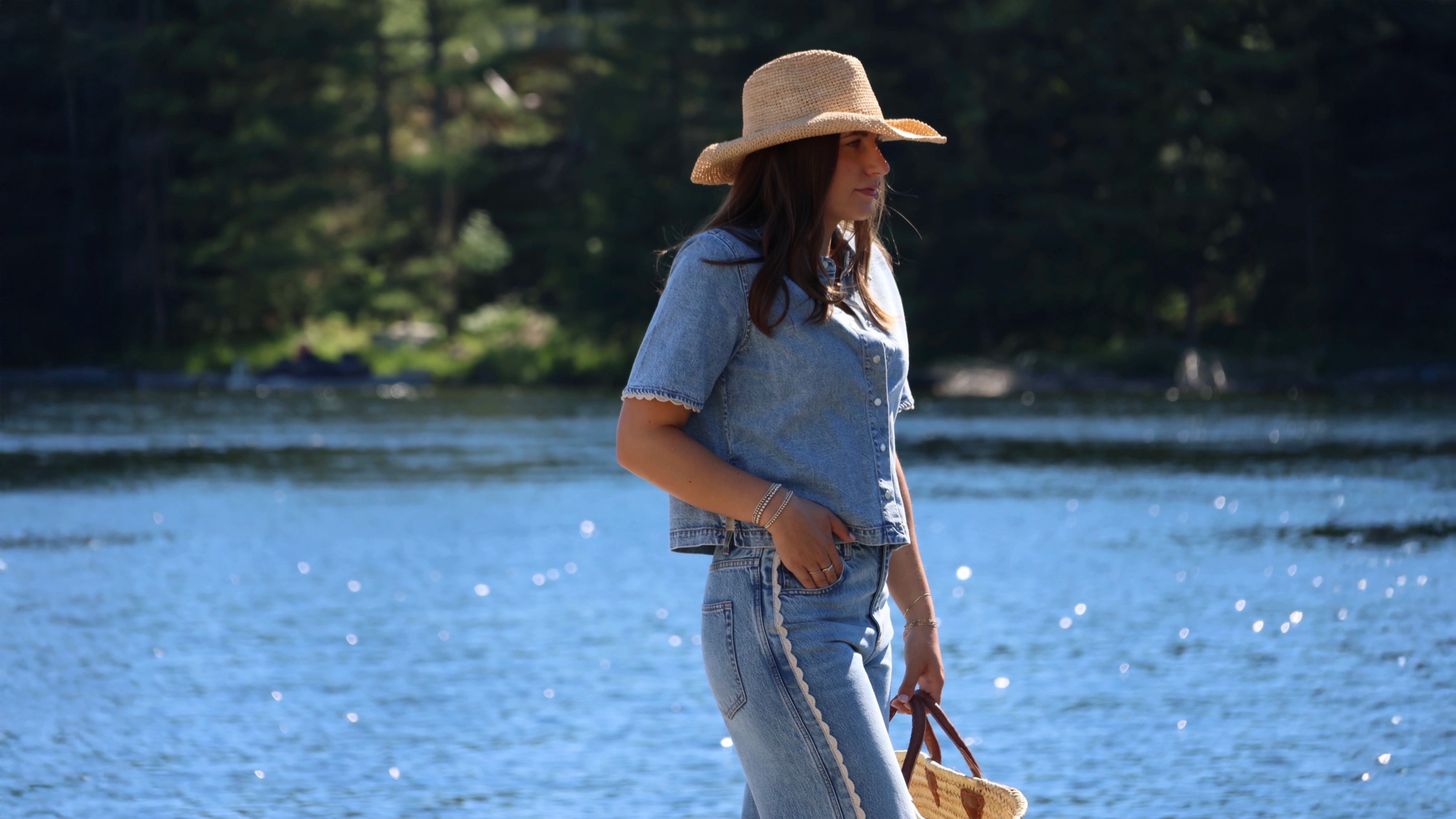 a woman wears denim outfit canadian tuxedo with straw beach hat in the muskokas