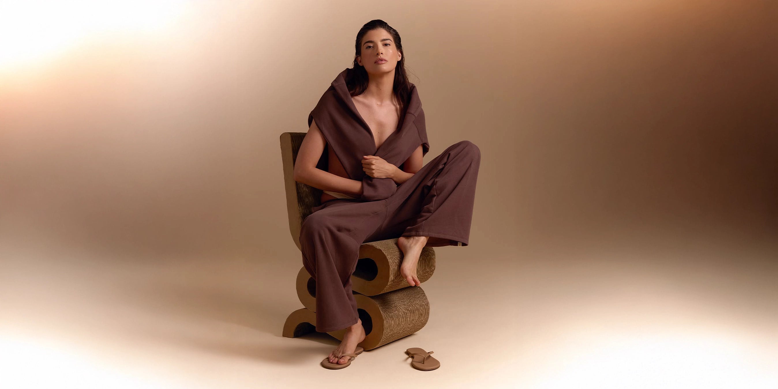 A woman wears jogging pants and sweater set in brown with flip flops