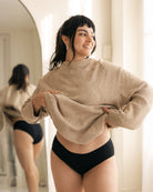 Woman wearing a beige sweater and black underwear