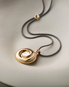 black rope necklace with a large gold pendant 