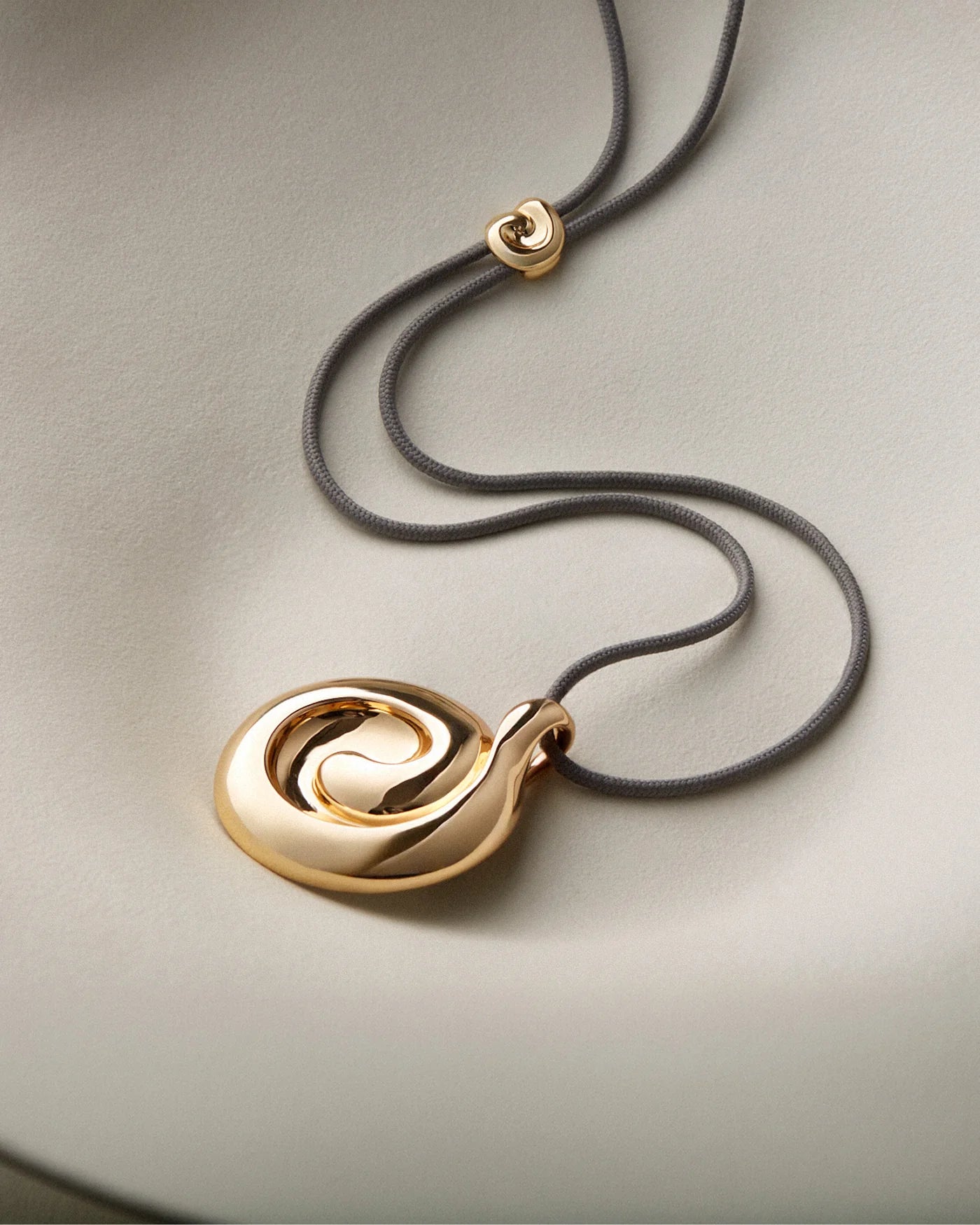 black rope necklace with a large gold pendant 