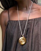 black rope necklace with a large gold pendant 