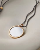 black rope necklace with a large gold pendant 