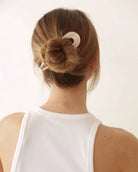 Person with a bun hairstyle using a pink French hair pin 