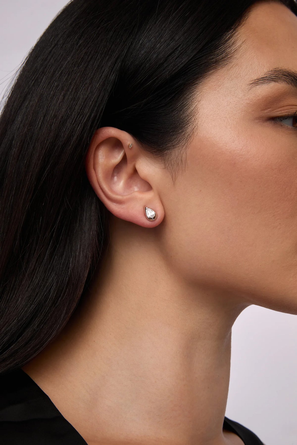 a woman wears a teardrop shaped crystal earring with silver by brand Lili Claspe