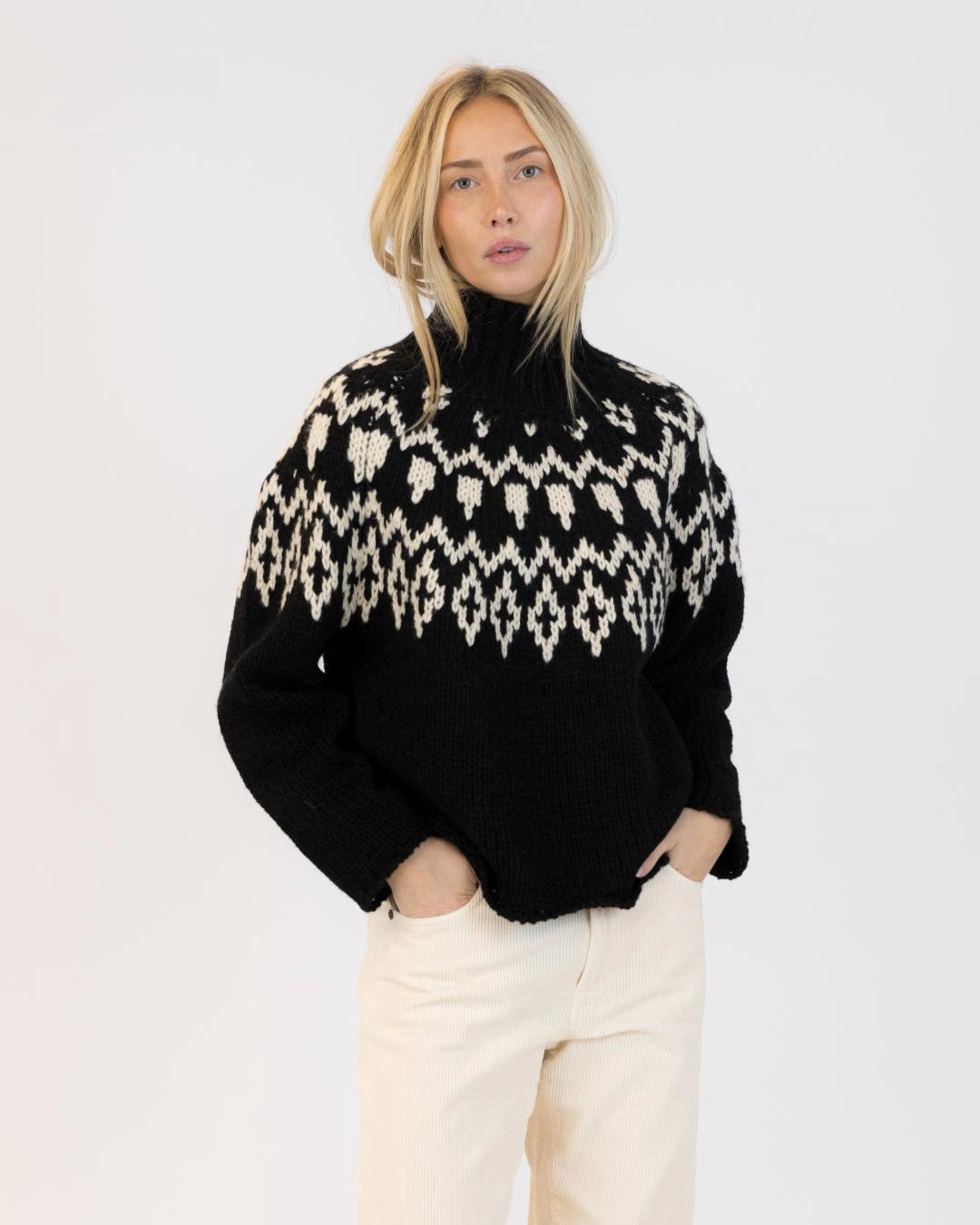 Woman wearing a fairisle sweater in blavk with cream accents
