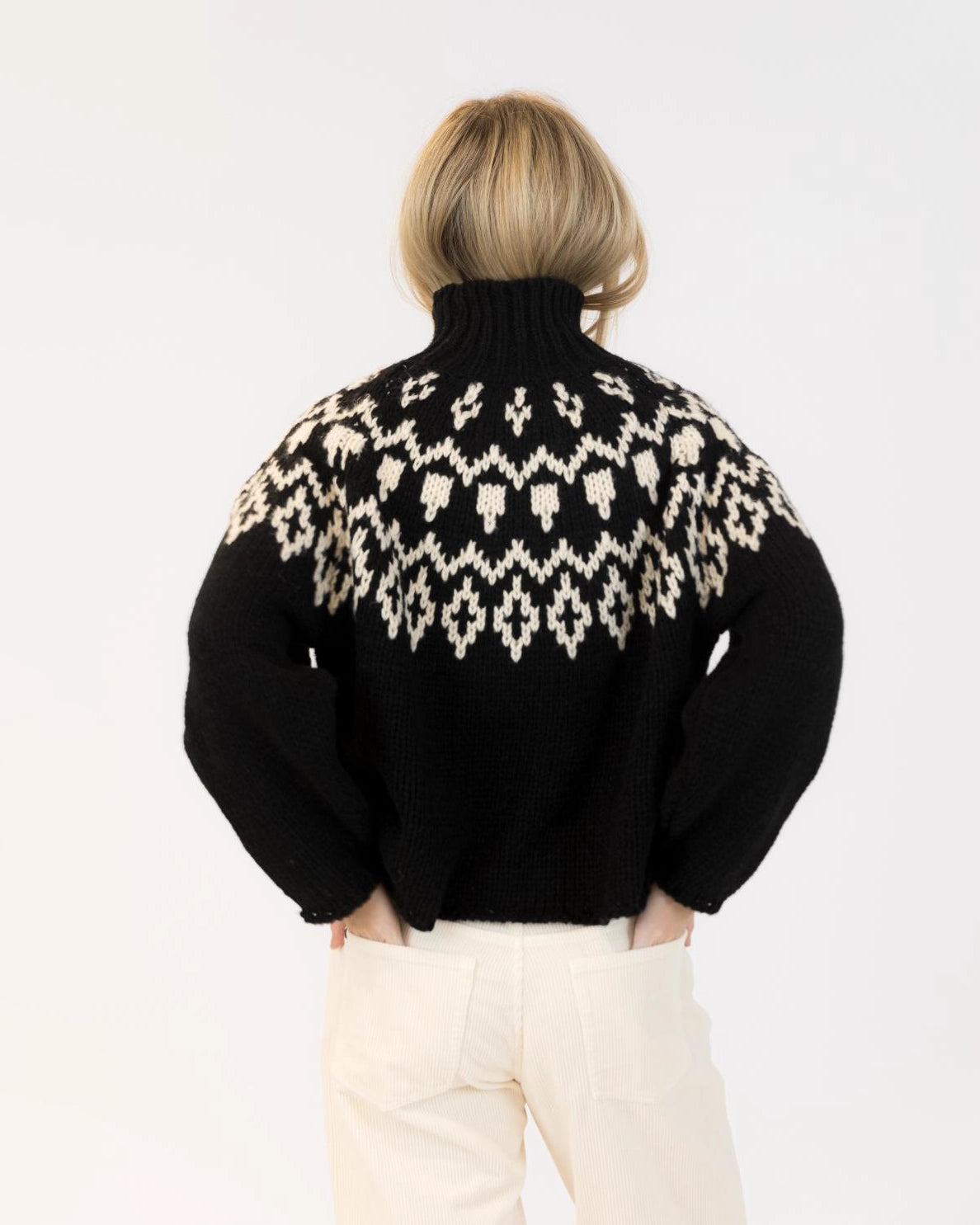 Woman wearing a fairisle sweater in blavk with cream accents