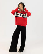 Woman wearing a red sweater with black and white accents with 'Après' on it