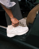 Person wearing a white sneaker stepping into a car.