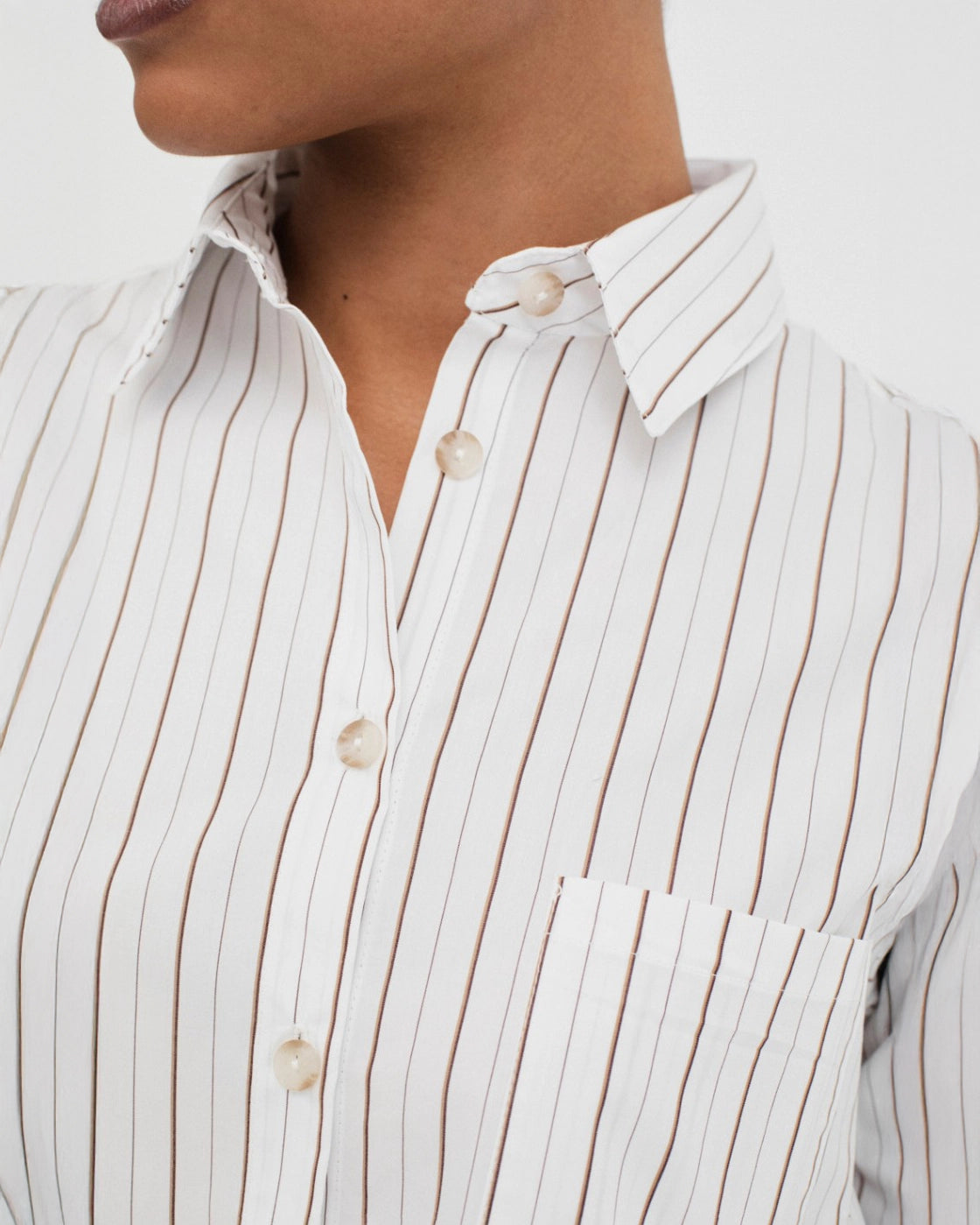 woman wearing a button up cotton shirt in white with brown stripes
