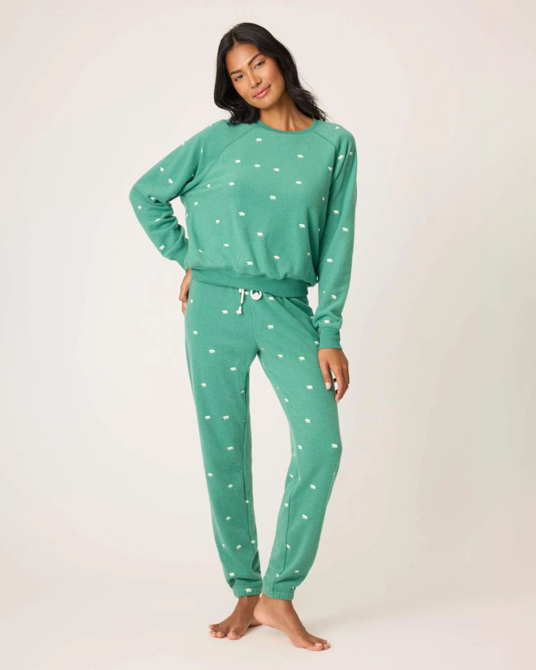 Woman wearing a green pajama set with white bears embroidered all over