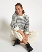 woman wearing a striped knit sweatshirt in cream and grey stripes