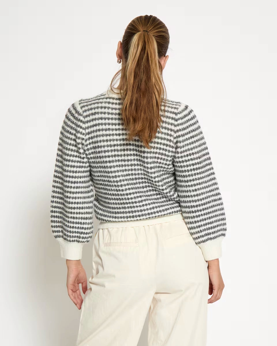 woman wearing a striped knit sweatshirt in cream and grey stripes