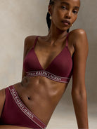 a model wears a branded triangle bralette by polo ralph lauren in a dark burgundy colour