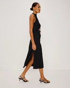 a woman wears a sleeveless black dress with a large lily on it in peach coral colour