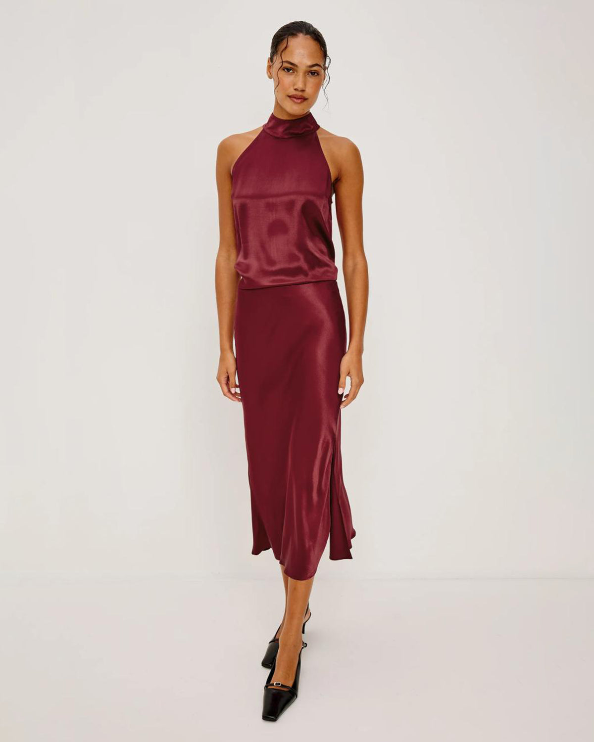 Woman wearing a burgundy satin halter top with matching satin skirt